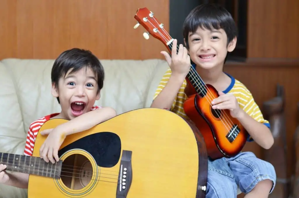 two happy kids playing guitar and uke