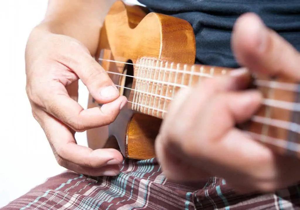 man strumming the ukulele close up