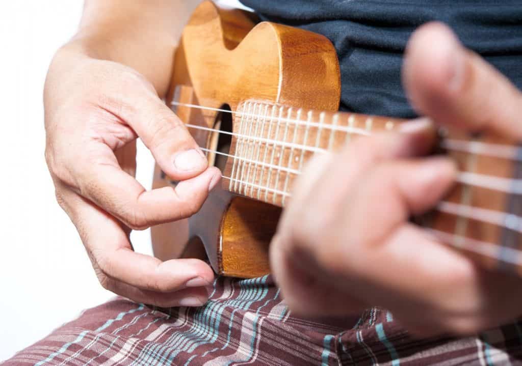 man strumming the ukulele close up