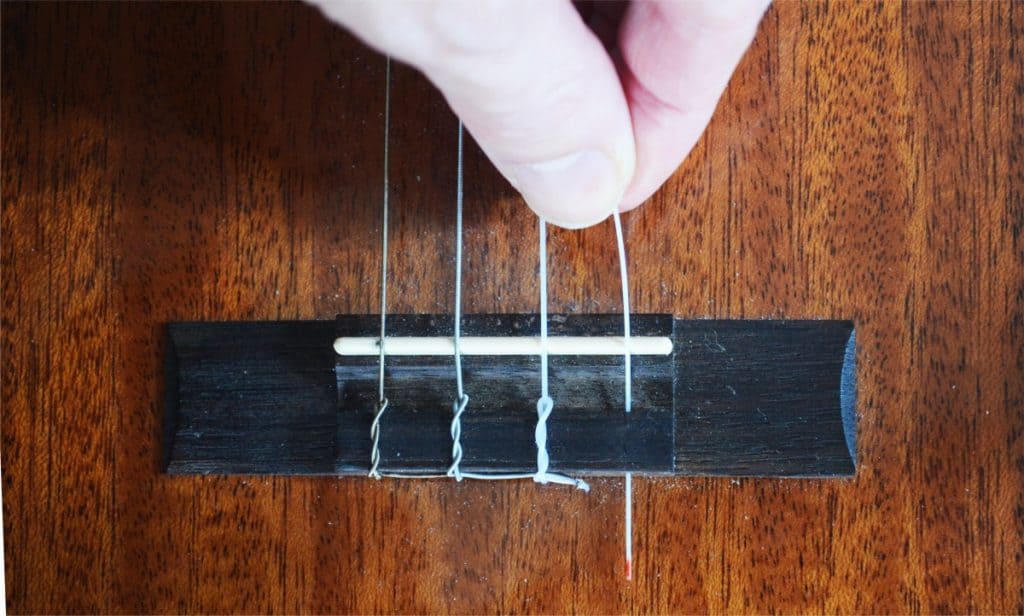 Step 2: Slide the string through the hole, from the saddle side (the white string bar).