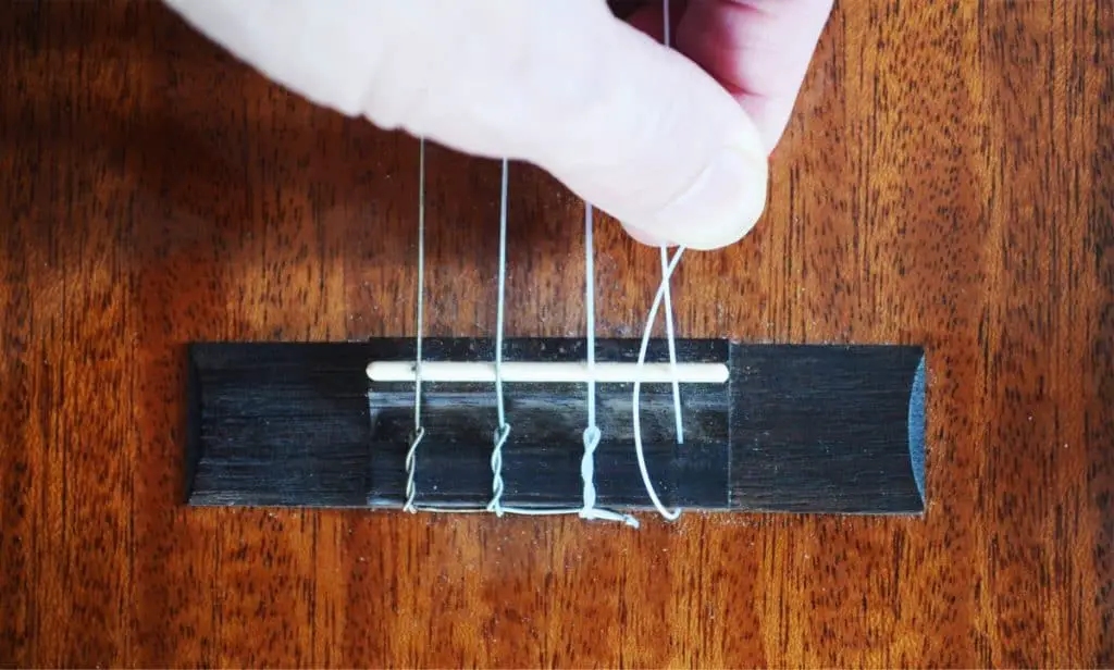 Step 3: Bring the shortest end of the string around to form an elongated 'O' shape and slip it under the main part of the string.