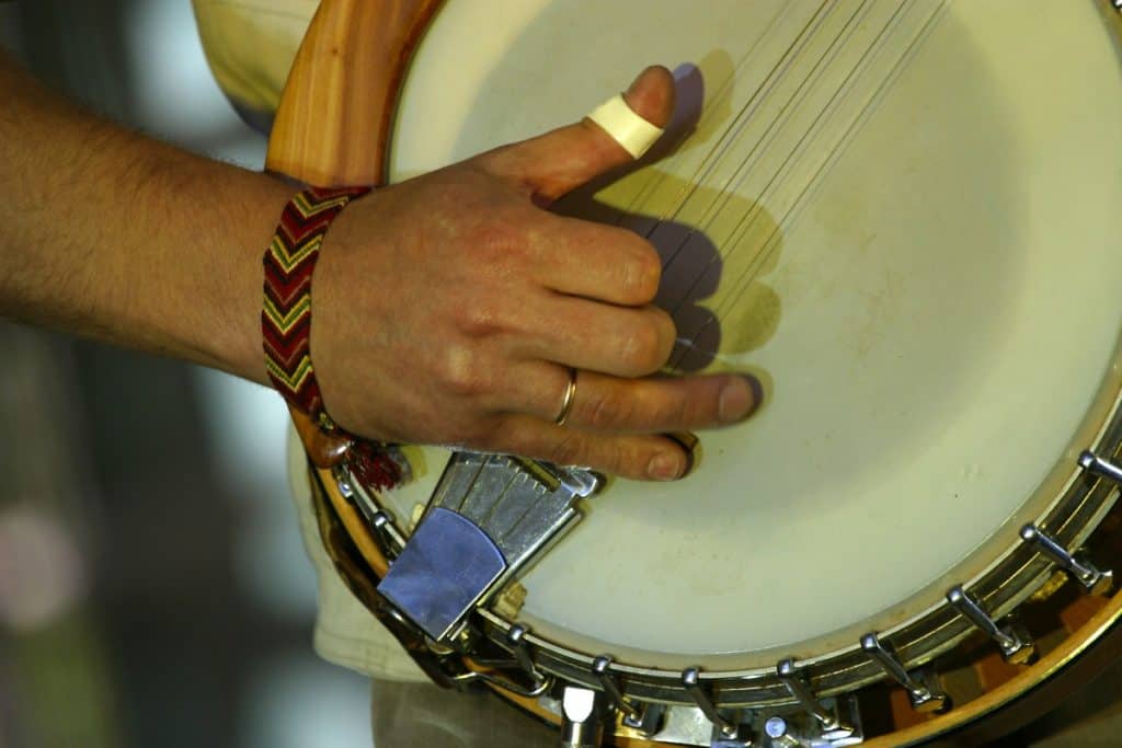 a man with a bandage on his finger still pursue to play the banjo 